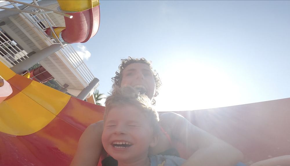 A parent and child laughing on a water slide